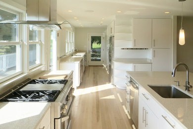 Inspiration for a modern galley light wood floor eat-in kitchen remodel in DC Metro with an undermount sink, flat-panel cabinets, white cabinets, quartz countertops, beige backsplash, stainless steel appliances and an island
