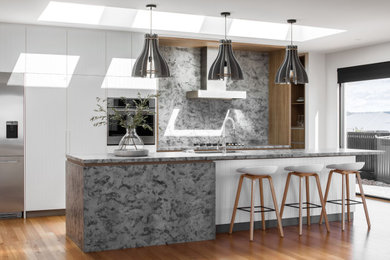 Foto de cocina moderna con puertas de armario blancas, encimera de granito, electrodomésticos de acero inoxidable, una isla y encimeras grises