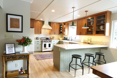 Eat-in kitchen - mid-sized country u-shaped light wood floor and beige floor eat-in kitchen idea in Seattle with a farmhouse sink, flat-panel cabinets, green cabinets, quartz countertops, gray backsplash, ceramic backsplash and white appliances
