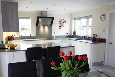 This is an example of a medium sized contemporary kitchen/diner in Manchester with flat-panel cabinets, quartz worktops, metallic splashback, stainless steel appliances, porcelain flooring and no island.