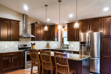 Example of a large classic medium tone wood floor and beige floor eat-in kitchen design in Other with an undermount sink, raised-panel cabinets, medium tone wood cabinets, granite countertops, beige backsplash, ceramic backsplash, stainless steel appliances and an island