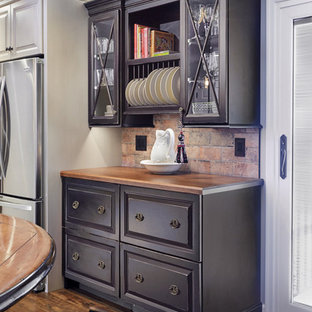 Inspiration pour une cuisine américaine traditionnelle en L de taille moyenne avec un évier encastré, un placard avec porte à panneau surélevé, des portes de placard noires, un plan de travail en granite, une crédence marron, une crédence en carreau de porcelaine, un électroménager en acier inoxydable, un sol en bois brun et un îlot central.