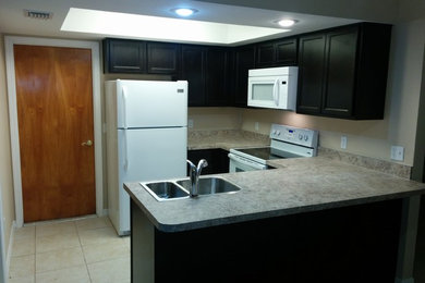 Example of a small trendy u-shaped ceramic tile eat-in kitchen design in Tampa with a double-bowl sink, flat-panel cabinets, dark wood cabinets, laminate countertops, white appliances and a peninsula