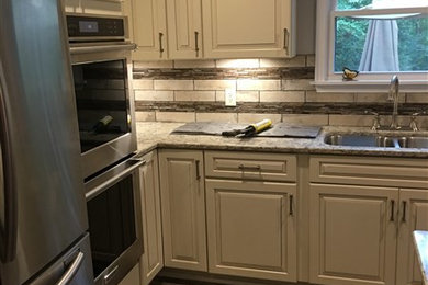 Inspiration for a mid-sized timeless l-shaped porcelain tile and gray floor eat-in kitchen remodel in Other with raised-panel cabinets, black cabinets, granite countertops, multicolored backsplash, ceramic backsplash, stainless steel appliances and an island