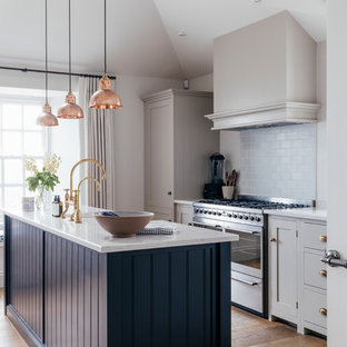 Mid-sized coastal kitchen pictures - Kitchen - mid-sized coastal galley medium tone wood floor and brown floor kitchen idea in Cornwall with a farmhouse sink, gray cabinets, solid surface countertops, blue backsplash, ceramic backsplash, stainless steel appliances, an island and white countertops