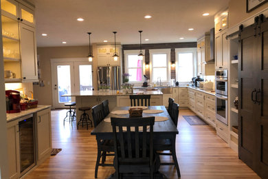 Inspiration for a large farmhouse l-shaped light wood floor and brown floor eat-in kitchen remodel in Indianapolis with an undermount sink, recessed-panel cabinets, white cabinets, granite countertops, gray backsplash, wood backsplash, stainless steel appliances, an island and multicolored countertops
