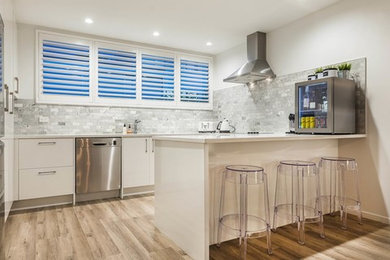 Imagen de cocina minimalista grande con salpicadero de azulejos de cerámica, electrodomésticos de acero inoxidable, suelo de madera clara y una isla