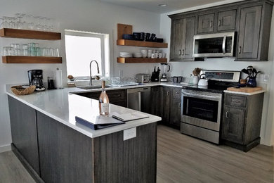 Mid-sized beach style u-shaped vinyl floor and gray floor eat-in kitchen photo in Boston with an undermount sink, beaded inset cabinets, gray cabinets, quartz countertops, stainless steel appliances and a peninsula
