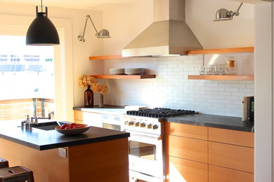 Example of a minimalist light wood floor kitchen design in San Francisco with a single-bowl sink, flat-panel cabinets, medium tone wood cabinets, soapstone countertops, white backsplash, ceramic backsplash, stainless steel appliances and an island