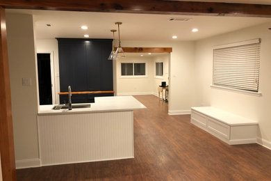 This is an example of a medium sized classic u-shaped open plan kitchen in New Orleans with a breakfast bar, shaker cabinets, white cabinets, quartz worktops, white splashback, white worktops, a submerged sink, ceramic splashback, stainless steel appliances, medium hardwood flooring, brown floors and exposed beams.