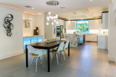 Eat-in kitchen - large modern u-shaped porcelain tile eat-in kitchen idea in Miami with an undermount sink, flat-panel cabinets, white cabinets, marble countertops, blue backsplash, glass sheet backsplash, stainless steel appliances and an island