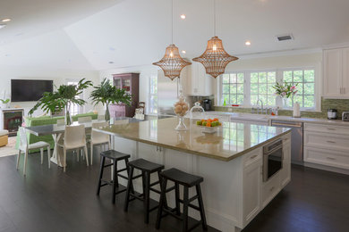 Example of an island style porcelain tile eat-in kitchen design in Miami with a farmhouse sink, shaker cabinets, white cabinets, green backsplash, stainless steel appliances and an island