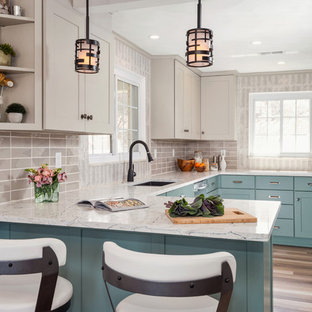 Foto di una cucina ad U tradizionale con lavello sottopiano, ante in stile shaker, ante blu, paraspruzzi grigio, elettrodomestici in acciaio inossidabile, parquet chiaro, penisola, pavimento beige e top bianco