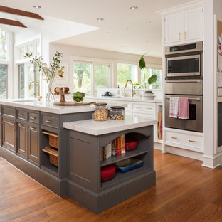 Transitional open concept kitchen inspiration - Transitional galley medium tone wood floor and brown floor open concept kitchen photo in New York with an undermount sink, recessed-panel cabinets, gray cabinets, stainless steel appliances and an island
