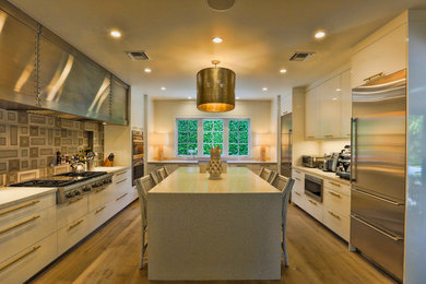 Large transitional u-shaped light wood floor enclosed kitchen photo in Miami with flat-panel cabinets, white cabinets, quartz countertops, stainless steel appliances and an island