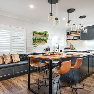 Transitional eat-in kitchen in Perth with shaker cabinets, black cabinets, white splashback, stainless steel appliances, medium hardwood floors, with island, brown floor and white benchtop.