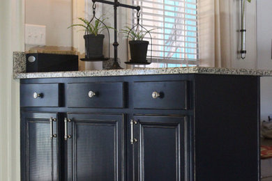 Diseño de cocina lineal de estilo de casa de campo con fregadero sobremueble, puertas de armario negras, encimera de granito, electrodomésticos negros y suelo marrón