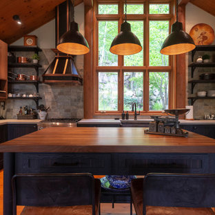 Mid-sized country u-shaped eat-in kitchen in Montreal with a farmhouse sink, flat-panel cabinets, medium wood cabinets, concrete benchtops, grey splashback, stone tile splashback, stainless steel appliances, medium hardwood floors, with island, orange floor and grey benchtop.
