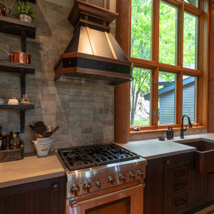 Design ideas for a mid-sized country u-shaped eat-in kitchen in Montreal with a farmhouse sink, flat-panel cabinets, medium wood cabinets, concrete benchtops, grey splashback, stone tile splashback, stainless steel appliances, medium hardwood floors, with island, orange floor and grey benchtop.