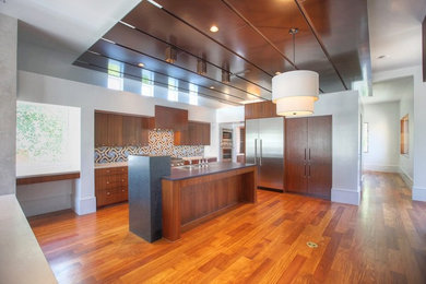 Example of a large trendy l-shaped medium tone wood floor and brown floor eat-in kitchen design in Houston with flat-panel cabinets, medium tone wood cabinets, multicolored backsplash, ceramic backsplash, stainless steel appliances and an island