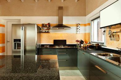 Imagen de cocinas en L minimalista con fregadero encastrado, armarios con paneles lisos, puertas de armario grises, encimera de granito y electrodomésticos de acero inoxidable