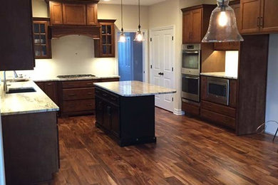 Example of a mid-sized classic u-shaped medium tone wood floor eat-in kitchen design in Chicago with a single-bowl sink, shaker cabinets, dark wood cabinets, granite countertops, white backsplash, stainless steel appliances and an island
