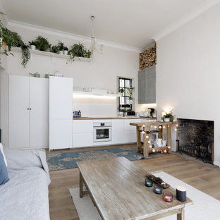Design ideas for a medium sized scandi single-wall open plan kitchen in Sussex with flat-panel cabinets, white cabinets, wood worktops, white splashback, integrated appliances, light hardwood flooring, an island, beige floors, beige worktops, a built-in sink and ceramic splashback.
