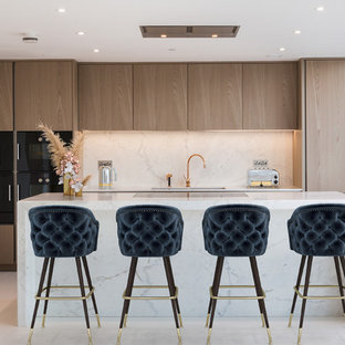 Design ideas for a contemporary galley kitchen in London with a submerged sink, flat-panel cabinets, medium wood cabinets, stainless steel appliances, an island, grey floors and white worktops.