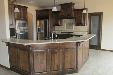 Mid-sized country u-shaped ceramic tile eat-in kitchen photo in Oklahoma City with raised-panel cabinets, medium tone wood cabinets, granite countertops, beige backsplash, ceramic backsplash, stainless steel appliances and a peninsula