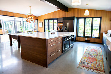 Example of a 1950s concrete floor kitchen design in Other with flat-panel cabinets and an island