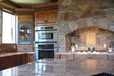 Aménagement d'une grande cuisine ouverte montagne en bois brun avec un placard avec porte à panneau surélevé, un plan de travail en granite, un électroménager en acier inoxydable, îlot et un plan de travail gris.