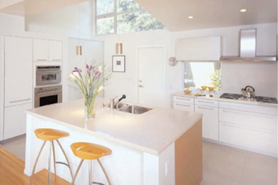 Inspiration for a large mid-century modern l-shaped white floor kitchen remodel in San Francisco with flat-panel cabinets, white cabinets, solid surface countertops, stainless steel appliances, an island and white countertops