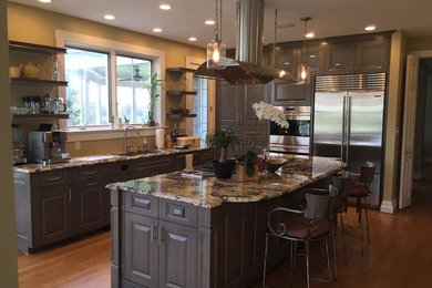 Inspiration for a mid-sized transitional medium tone wood floor eat-in kitchen remodel in Baltimore with a single-bowl sink, gray cabinets, granite countertops, metallic backsplash, mosaic tile backsplash, stainless steel appliances, an island and raised-panel cabinets