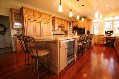 Example of a classic l-shaped eat-in kitchen design in Indianapolis with raised-panel cabinets, medium tone wood cabinets, granite countertops, brown backsplash, ceramic backsplash and paneled appliances