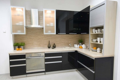 Inspiration for a mid-sized transitional l-shaped white floor open concept kitchen remodel in Phoenix with a single-bowl sink, glass-front cabinets, black cabinets, beige backsplash, stainless steel appliances and no island