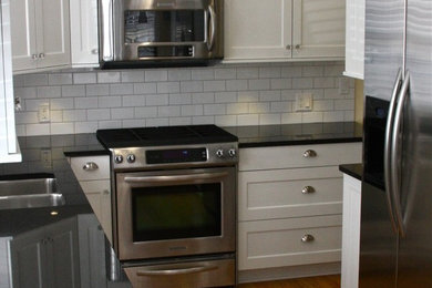 グランドラピッズにある高級な広いトラディショナルスタイルのおしゃれなキッチン (ダブルシンク、落し込みパネル扉のキャビネット、白いキャビネット、白いキッチンパネル、サブウェイタイルのキッチンパネル、シルバーの調理設備、濃色無垢フローリング) の写真