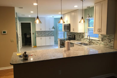 Inspiration for a large transitional l-shaped ceramic tile eat-in kitchen remodel in Jacksonville with an undermount sink, white cabinets, granite countertops, gray backsplash, glass tile backsplash, stainless steel appliances and no island