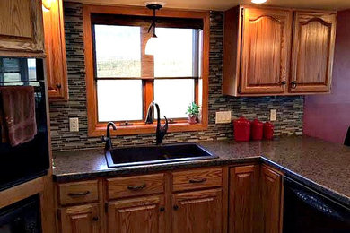 Example of a large classic u-shaped enclosed kitchen design in Cedar Rapids with a drop-in sink, raised-panel cabinets, dark wood cabinets, granite countertops, multicolored backsplash, matchstick tile backsplash, black appliances and a peninsula