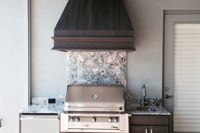 Modelo de cocina lineal tradicional de tamaño medio con fregadero encastrado, armarios con puertas mallorquinas, puertas de armario de madera en tonos medios y encimera de granito