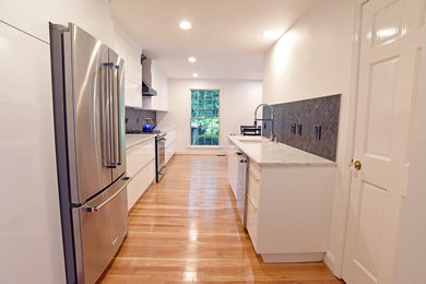 Inspiration for a mid-sized contemporary l-shaped medium tone wood floor eat-in kitchen remodel in DC Metro with an undermount sink, flat-panel cabinets, white cabinets, solid surface countertops, black backsplash, stone tile backsplash, stainless steel appliances, no island and white countertops