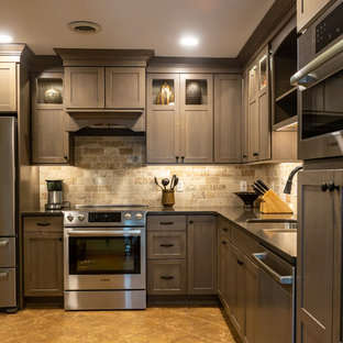 Mid-sized rustic enclosed kitchen designs - Example of a mid-sized mountain style l-shaped travertine floor and beige floor enclosed kitchen design in Other with a double-bowl sink, glass-front cabinets, quartz countertops, travertine backsplash, stainless steel appliances, no island, black countertops, medium tone wood cabinets and beige backsplash
