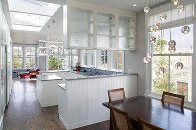 Идея дизайна: кухня-гостиная среднего размера в стиле ретро с стеклянными фасадами, белыми фасадами, синим фартуком, темным паркетным полом, островом и коричневым полом
