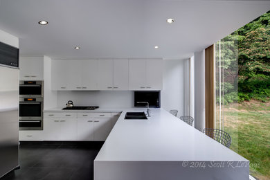 Minimalist enclosed kitchen photo in New York with flat-panel cabinets, white cabinets, white backsplash and stainless steel appliances