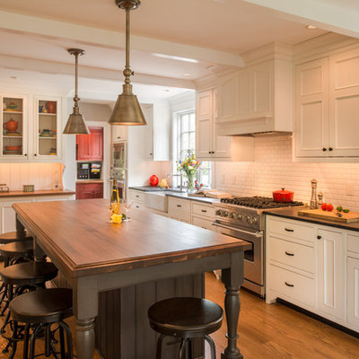 Eat-in kitchen - large traditional l-shaped medium tone wood floor eat-in kitchen idea in Philadelphia with a farmhouse sink, white cabinets, wood countertops, white backsplash, subway tile backsplash, beaded inset cabinets, stainless steel appliances and an island