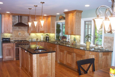 Inspiration for a timeless l-shaped light wood floor enclosed kitchen remodel in Detroit with an undermount sink, flat-panel cabinets, light wood cabinets, granite countertops, beige backsplash, stone tile backsplash, stainless steel appliances and an island