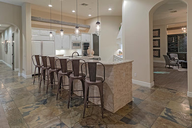 Open concept kitchen - large traditional u-shaped travertine floor open concept kitchen idea in Phoenix with a triple-bowl sink, recessed-panel cabinets, white cabinets, granite countertops, white backsplash, subway tile backsplash, white appliances and an island