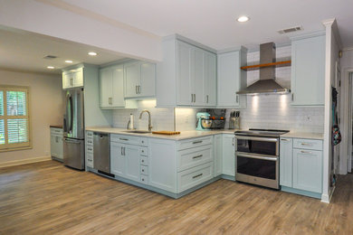 Example of a mid-sized beach style single-wall medium tone wood floor and brown floor eat-in kitchen design in Other with an undermount sink, shaker cabinets, turquoise cabinets, white backsplash, subway tile backsplash, stainless steel appliances, no island and beige countertops