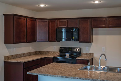 Moderne Wohnküche mit braunen Schränken, Granit-Arbeitsplatte und Kücheninsel in Sonstige