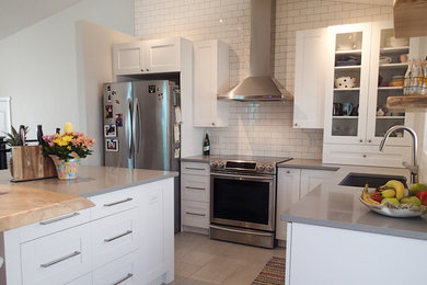 Inspiration for a mid-sized transitional l-shaped porcelain tile and gray floor kitchen pantry remodel in Calgary with an undermount sink, shaker cabinets, white cabinets, quartzite countertops, white backsplash, ceramic backsplash, stainless steel appliances and an island