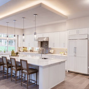 Mid-sized contemporary open concept kitchen ideas - Mid-sized trendy l-shaped light wood floor and beige floor open concept kitchen photo in Seattle with a farmhouse sink, shaker cabinets, white cabinets, quartz countertops, metallic backsplash, paneled appliances, an island and white countertops